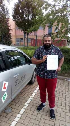 Bilal from BD3 smiling with his pass certificate after passing his driving test on his first attempt at Thornbury test centre in Bradford with SUX-S Driving School.