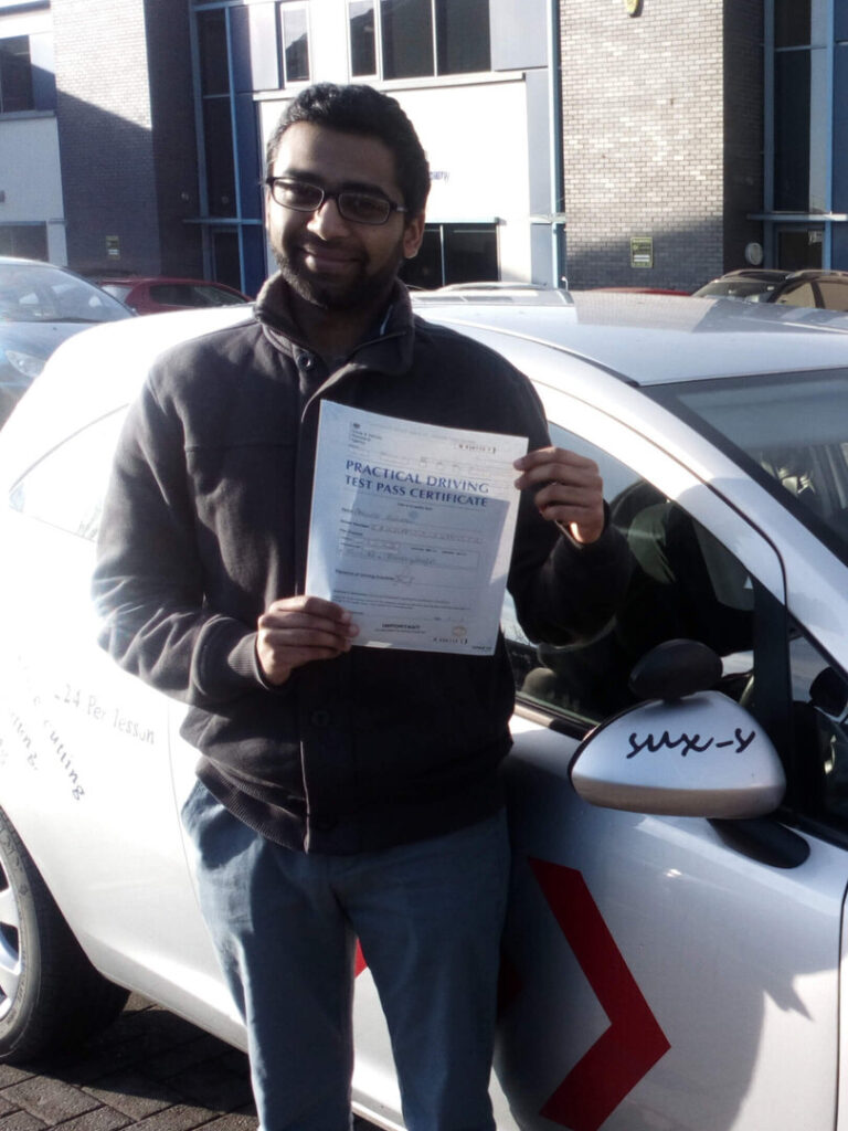 Aminoor smiling while holding his driving test pass certificate after passing on his first attempt at the Thornbury test centre in BD3 Bradford with SUX-S Driving School.