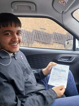 Kamran holding his driving test pass certificate after passing on his first attempt in BD3 Bradford with SUX-S Driving School.