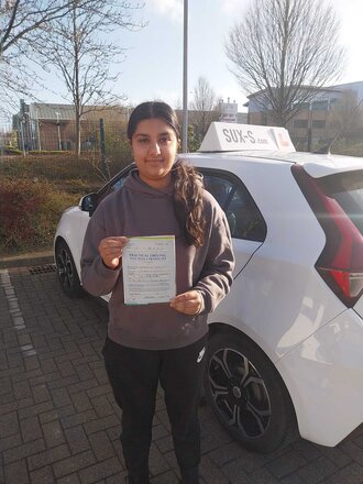 Shabana smiling with her driving test pass certificate after passing on her first attempt at the Thornbury test centre in BD3 Bradford with SUX-S Driving School.